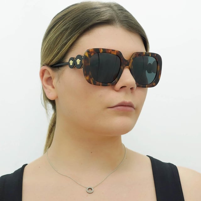 Versace Square Womens Black Dark Grey VE4434  Sunglasses are a bold and striking eyewear option that blends modern design with luxury details. With a square frame made of high-quality acetate, these sunglasses feature tinted lenses that provide 100% UV protection. The Medusa head emblem and gold-tone detailing on the temples add a touch of glamour to the design.