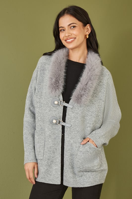 This cute cardi is perfect for cosying up this winter - In a soft marl knit with buckle fastening in the front and faux fur detachable collar. Style with jeans and a roll neck jumper - With boots or trainers for a casual off duty look.