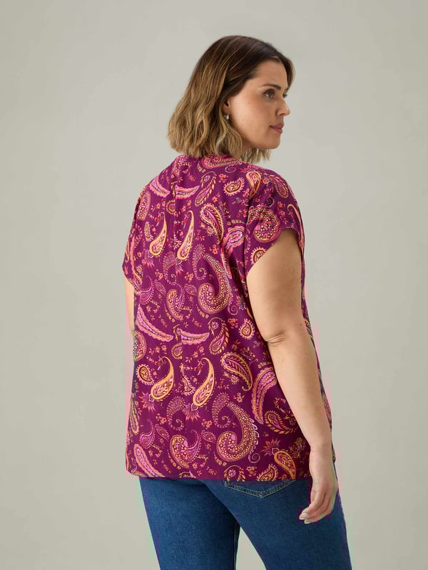 In a pretty purple-red paisley print, this pleat front top is cut from a lightweight woven fabric thats so comfortable to wear. With a lengthening V-neck, this top has short sleeves and pleat detailing through the centre front which complements its loose, A-line body. Pair this with jeans or leggings for the perfect laid-back look.