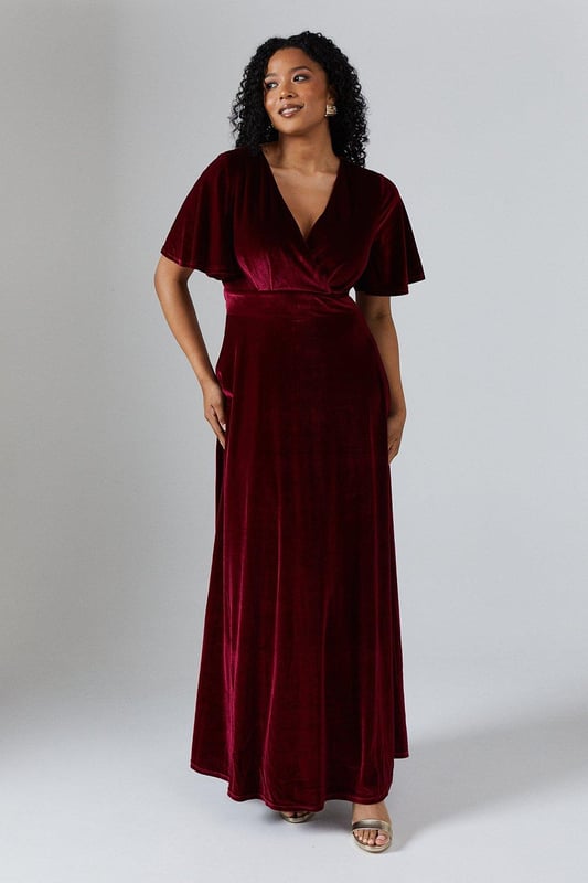 Luxurious velvet fabric for a sumptuous look and feel
        Flattering V-neckline to enhance the dcolletage
        Angel sleeves for a romantic and ethereal touch
        Floor-sweeping maxi length for a dramatic silhouette
        Fitted waist to accentuate the figure
    
    This enchanting V Neck Angel Sleeve Velvet Bridesmaids Maxi Dress from Coast is the epitome of sophistication and grace. Perfect for the bridal party, this gown is designed to complement the bride while ensuring you stand out in your own right. The sumptuous velvet fabric drapes beautifully, creating a fluid silhouette that moves elegantly as you walk. The angel sleeves add a whimsical touch, while the V-neckline draws attention to the dcolletage. The fitted waist cinches in to create an hourglass shape, flowing into a full-length skirt that skims the floor. Pair with delicate strappy heels and minimal jewellery to let the dress take centre stage. This gown is versatile enough to be worn again for other formal occasions, making it a treasured addition to your wardrobe long after the wedding bells have rung.