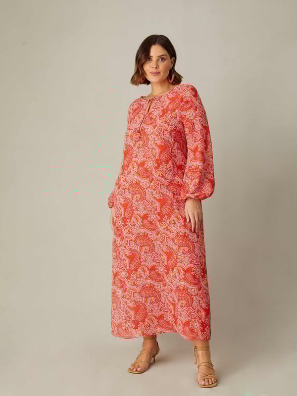 Printed all over with a pretty red paisley print, this dress is cut from a soft woven fabric that moves beautifully. It has a V-neckline with fixed tie detailing, as well as full-length raglan sleeves with elasticated cuffs. Its maxi length makes it the perfect throw-on piece, ideal for any holiday or summer look.