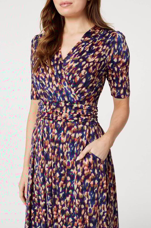 Add a comfortable jersey dress to your wardrobe with this printed midi. It has a v-neck with a faux wrap front, 1/2 sleeves, a flattering ruched waist and a straight midi length skirt. Pair with heels or boots for a go-to style to wear during transitional seasons.