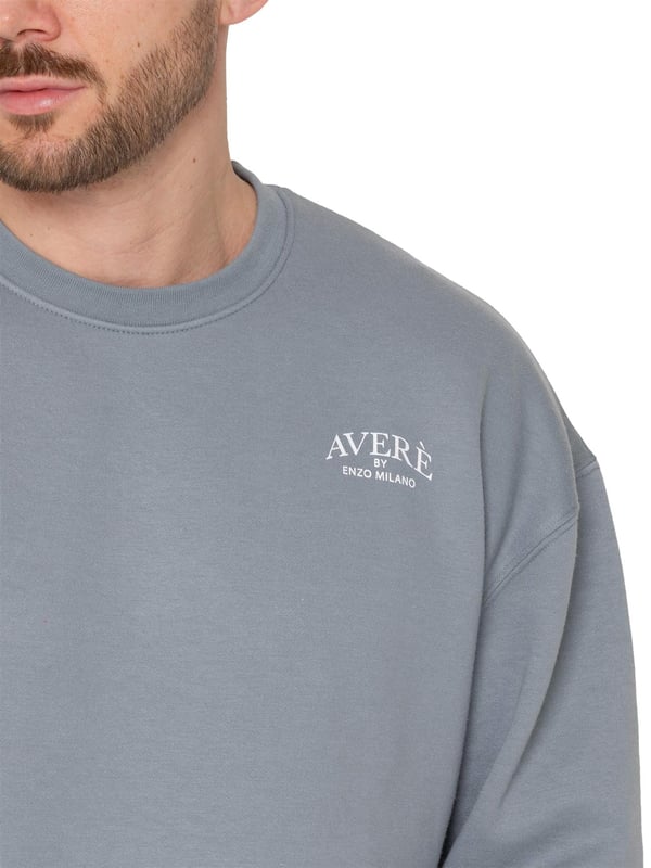 El suéter oversized para hombre Averè de Enzo Milano presenta un ajuste relajado y casual, perfecto tanto para descansar como para el uso diario. El frente muestra un discreto logotipo de Averè en el pecho. El suéter tiene mangas largas y un cuello redondo acanalado con puños acanalados, lo que le da una silueta limpia y clásica. La tela suave y el forro de felpa garantizan comodidad, mientras que el corte de hombro caído mejora el aspecto oversized. La parte trasera permanece lisa, manteniendo un estilo simple y elegante. Ideal para combinar con pantalones de chándal o jeans para un atuendo relajado.
