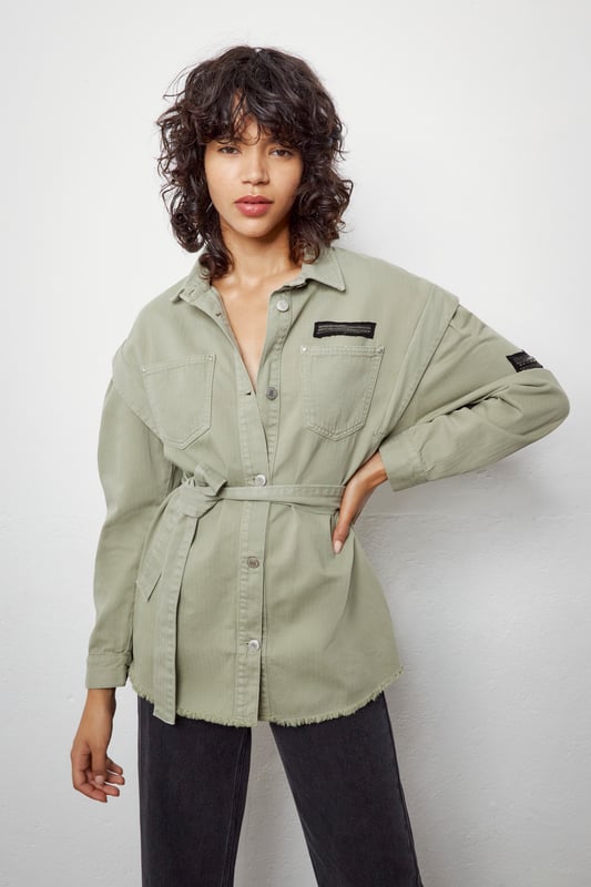 This khaki shirt with removable belt has military badges on the chest and sleeve and two patch pockets on the chest. It has a shirt collar, long sleeves, details at the shoulders and a ripped effect on the bottom. Button fastening.