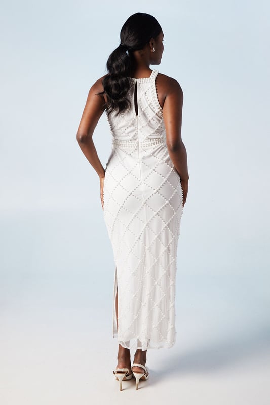 Stunning geometric pearl embellishment
        Elegant halterneck design
        Figure-flattering column silhouette
        Sophisticated midi length
        Delicate hand-stitched detailing
    
    Make a lasting impression on your special day with this exquisite bridal dress from Coast. The intricate geometric pattern adorned with pearls creates a mesmerising visual effect, perfect for the modern bride who desires a touch of glamour. The halterneck style elegantly frames the dcolletage, while the column silhouette gracefully skims your curves. Pair with strappy heels and pearl drop earrings for a cohesive bridal look. This dress is versatile enough for various wedding venues, from a chic city celebration to a romantic beach ceremony. The midi length offers practicality without compromising on style, allowing you to move with ease during your first dance and beyond. This Coast creation is a testament to timeless elegance, ensuring you feel confident and radiant as you embark on your new chapter.
