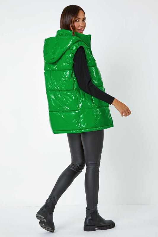 Patent Hooded Gilet from Roman. Add a pop of colour and a unique twist to your casualwear with our bold hi-shine gilet! The perfect layer for transitioning into Autumn, this cosy staple has a padded silhouette and cosy funnel neckline for warmth. With a secure zip fastening, this jacket also has drawstring detail and a glossy high shine finish. This statement jacket is a fashionable yet functional layering piece with zipped side pockets and a showerproof hood. Wear over relaxed denim and lightweight jumper for your own runway inspired outfit!