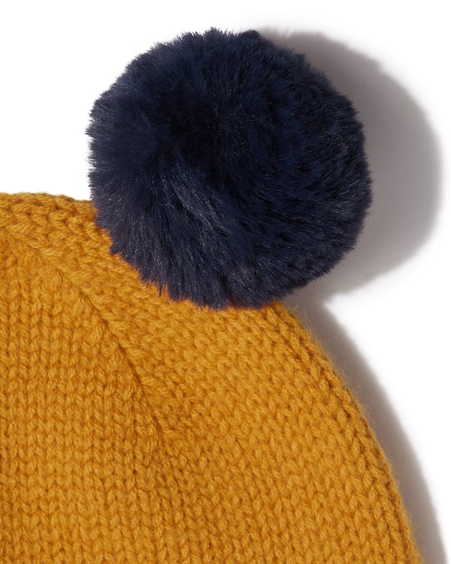 Keep your little one cosy this winter with this adorable wool hat featuring faux fur pom poms. Team with matching scarf and gloves for a cute combination. Available in classic navy and on-trend mustard.