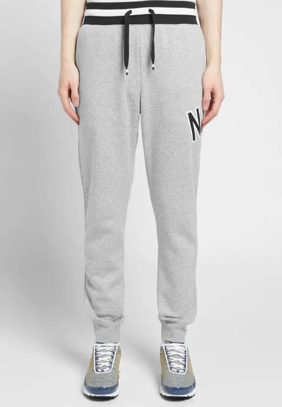 Nike Air heren trainingspak met doorlopende ritssluiting in grijs. Capuchon met trekkoord, ritssluiting, geborduurde Swoosh. Gedrukte branding, opgesplitste kangoeroezak. Geweven merkpatch, geribbelde manchetten en zoom. Elastische tailleband. Elastische taille joggingbroek met trekkoord. Geribbelde onderbeenmanchetten voor een comfortabele pasvorm.