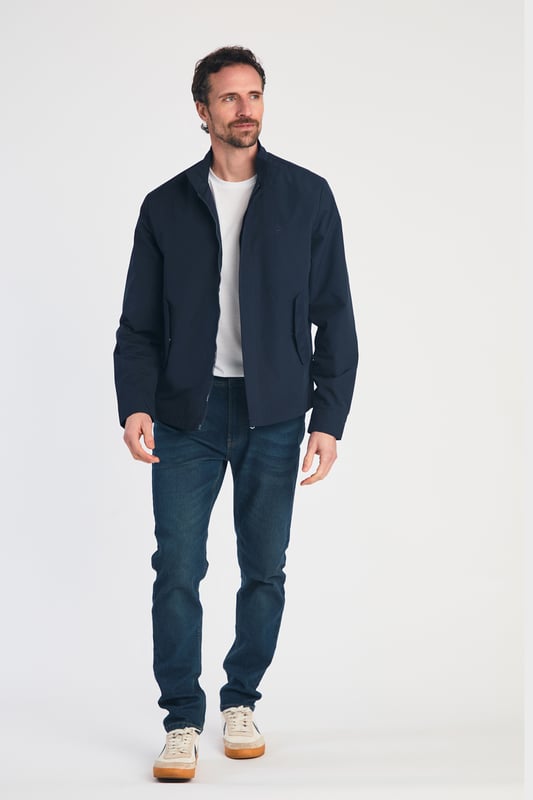 This Harrington Style Jacket by Kensington Eastside features a button-up collar, pop button sleeves, and a durable PVC coating. The checked mesh inner lining enhances comfort, while two side pockets and an embroidered logo add style and functionality, making it a perfect choice for casual wear.