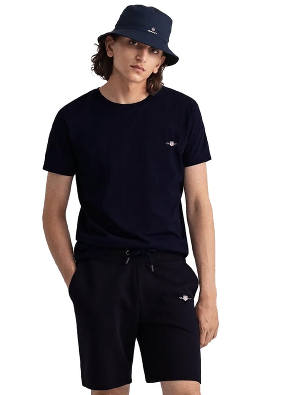 Gant introduces a mens t-shirt and shorts set with a small-scale embroidered shield graphic on the chest. Made of soft cotton and featuring a ribbed neckline, this tee showcases the iconic GANT logo. Crafted for everyday wear, the regular-fit tee is both comfortable and sustainable with Better Cotton. The included sweat shorts, also made of soft cotton blend, feature a ribbed waistband, three pockets, and a drawstring waist. The shorts are adorned with a small-scale embroidered shield graphic.