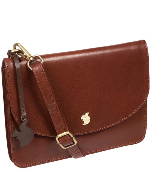The 'Cara' cross body clutch bag from Conkca London is handcrafted from multi-toned leather for a beautiful finish. A magnetic press-stud secured cover opens to reveal the spacious interior that is lined with natural and untreated 100% cotton and includes two slip pockets. A full-width slip pouch on the rear of the bag is ideal for on-the-go storage. It comes with an adjustable leather strap with a maximum drop length of 70cm which is removable, converting the bag into a clutch bag. Adorned with the inimitable Conkca squirrel charm and metal logo.