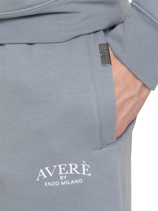 Presentamos el Conjunto de Chándal con Sudadera con Capucha Oversized Averè para Hombre de Enzo Milano, una mezcla perfecta de comodidad y estilo. Este set incluye una Sudadera con Capucha Oversized con un suave forro de felpa, un logotipo sutil en el pecho, un diseño audaz en la parte trasera y una capucha con botones a presión. Los Joggers de Corte Regular tienen una cintura elástica, cordones ajustables, bolsillos laterales y puños acanalados en los tobillos para un ajuste seguro. Ideal para relajarse o para salidas casuales, este chándal ofrece un estilo relajado y a la moda