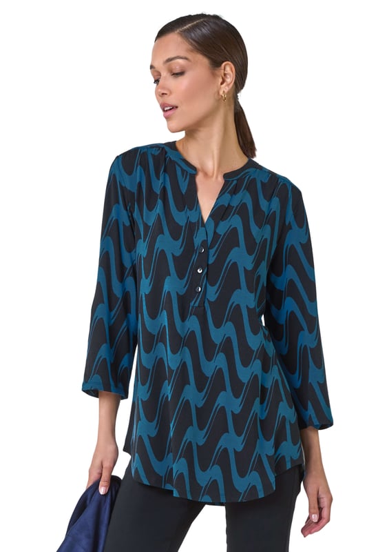 Geometric Print Stretch Blouse from Roman. Elevate your wardrobe this season with our stunning abstract blouse. The bold print and woven silhouette make it versatile for any occasion. The notch neckline, adjustable 3/4 length sleeves and front button details adds a touch of sophistication. Pair it with black jeans and boots for a daytime look or add tailored trousers perfect for those desk-to-dinner days