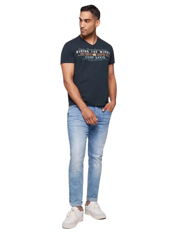 Dieses Herren-T-Shirt vereint lässigen Stil mit raffinierter Detailverliebtheit. Der V-Ausschnitt mit Used-Kante verleiht dem Shirt einen coolen, entspannten Look. Die Flammgarnstruktur sorgt für eine einzigartige Textur und unterstreicht die Individualität des Designs. Kontrastnähte an den Schultern setzen subtile Akzente, die das Gesamtbild perfekt abrunden. Ein markanter Front-Print mit Flockprint-Details zieht alle Blicke auf sich, während ein kleiner Logo-Print hinten und ein Label-Patch am linken Ärmel dezente Markenakzente setzen. Das Necktape sorgt für zusätzlichen Tragekomfort und Stabilität. Mit seiner normalen Passform und dem hohen Tragekomfort ist dieses Shirt ein Must-have für jeden Kleiderschrank. Ideal für lässige Outfits, die dennoch Stilbewusstsein ausstrahlen. Ein zeitloses Stück, das in keiner Garderobe fehlen sollte.