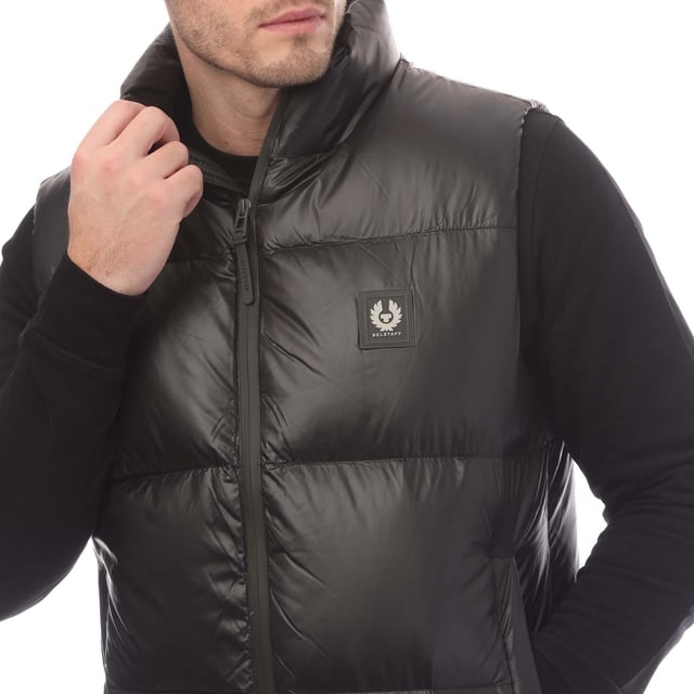 Mens Belstaff Down Filled Ripstop Resolve Gilet in black.- Hood and hem drawcord.- Water resistant double centre front zip.- Zip fastening hip pockets.- Silicone phoenix badge on the chest.- Packable functionality.- 750 fill power down.- 100% RDS certified down and feather (IDFL CERT TE-00103785) with PFAS free water-repellent finish.- High-shine  100% recycled nylon in a micro ripstop construction.- High performance  lofty  ultralight and highly insulating down gilet style.- 100% Polyamide.- Ref: 105160BLACK
