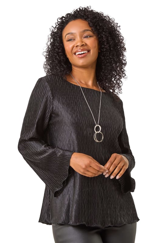 Petite Pleated Necklace Top from Roman. Add a touch of glamour to your Winter wardrobe with this statement petite top. Crafted from a pleated woven fabric, this round neck top features chic long sleeves and a flattering hip-length finish. The standout feature is the attached necklace trim, adding a touch of sparkle and eliminating the need for extra accessories. Easy to wear and effortlessly stylish, pair this top with tailored trousers and heels for a sophisticated look that transitions seamlessly from day to night!