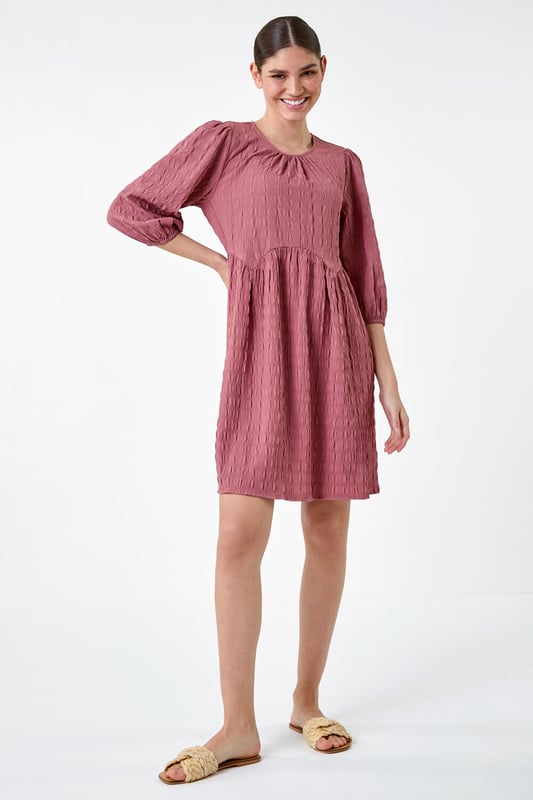 Bubble Textured A-Line Stretch Dress from Roman. Add pretty textures to your everyday collection this season, with this easy-to-wear A-line dress. Crafted from a stretch jersey fabric, this piece features a modest round neckline and 3/4 length sleeves, finished with elasticated cuffs. An empire waistline ensures a flattering and comfortable fit, while the all-over texture provides interest throughout. Pair with sandals and a denim jacket for a laid-back look, or add wedges and a sun hat for a day at the beach club!