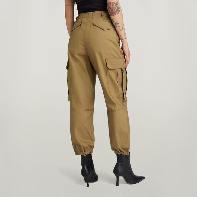 Flap pockets at the waist and back- hidden snap button. Cargo pockets at the thigh- hidden snap closure. Adjustable leg hem- Integrated tape. Zip & button closure. High waist. Cargo pants Drawcord show a straight fit with a shortened length. The straps at the back allow for a tighter waist. The pleats at the knee add more shape. The cargo pockets show an additional pull strap. 70% Cotton, 30% Cotton (Recycled). Canvas woven. Peach finish, soft touch. Straight