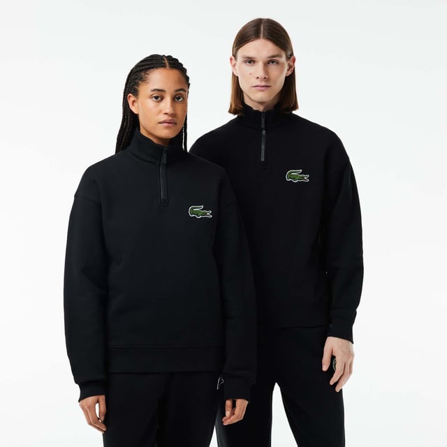 Unisex Lacoste Loose Fit High Neck Sweatshirt in Black. Finest materials, brand’s singular expertise. The perfect expression of Lacoste’s timeless wardrobe.- Loose fit is loose ease on body and sleeves, lower shoulders and armholes.- Half zipped sweatshirt in organic heavy French terry with big croc 80' on chest.- Unisexe.- Zipped high collar in shell fabric.- 7cm iconic original badge crocodile.- 3cm green crocodile at under middle back collar. Material: 100% Organic Cotton. Ref: SH0069031.