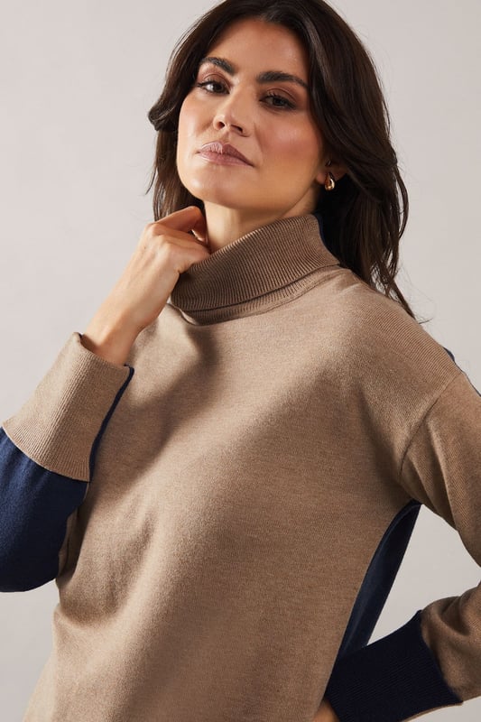 Asymmetric hem design for a modern twist
        Cosy roll neck for extra warmth and style
        Contrasting cuffs add a unique touch
        Relaxed tunic silhouette for comfort
        Versatile knitted fabric suitable for various occasions
    
    This Roll Neck Asymmetric Hem Tunic from Wallis is the epitome of sophisticated comfort. The asymmetric hem creates a flattering silhouette, while the roll neck offers both warmth and elegance. Perfect for those who appreciate a touch of glamour in their everyday wear, this tunic can be styled for various occasions. Pair it with wide-leg trousers and ballet flats for a chic daytime look, or dress it up with tailored trousers and heeled boots for evening gatherings. The contrasting cuffs add a subtle yet striking detail, making this piece stand out in your wardrobe. Whether you're attending a family lunch or meeting friends for coffee, this versatile tunic will keep you looking polished and feeling comfortable throughout the day.
