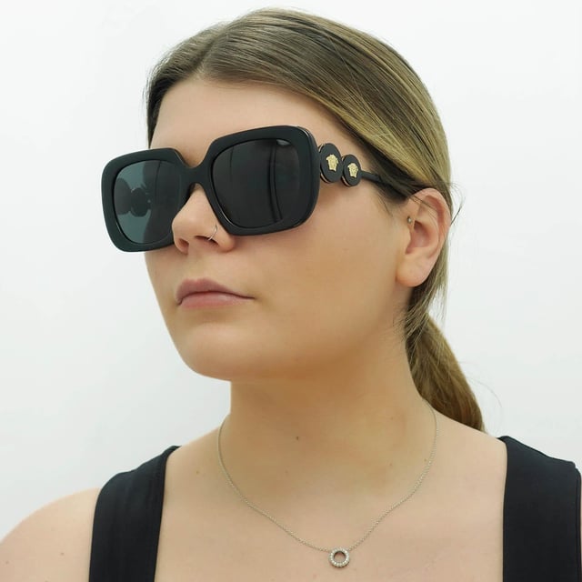 Versace Square Womens Black Dark Grey VE4434  Sunglasses are a bold and striking eyewear option that blends modern design with luxury details. With a square frame made of high-quality acetate, these sunglasses feature tinted lenses that provide 100% UV protection. The Medusa head emblem and gold-tone detailing on the temples add a touch of glamour to the design.
