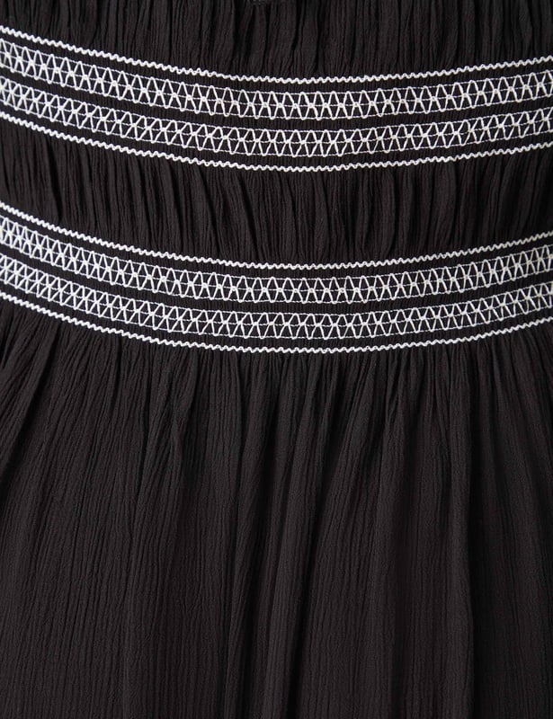 In classic black, this dress is cut from a soft, textured fabric thats so comfortable to wear. With elasticated shirring through the bodice in contrasting white, it has a flattering square-neck shape. Elastication around the neck and shoulder heads ensures comfort, while a cross-shoulder tie prevents the full-length sleeves from falling down. It has a stylish midaxi shape with a flowy skirt, making this the perfect warm weather piece.