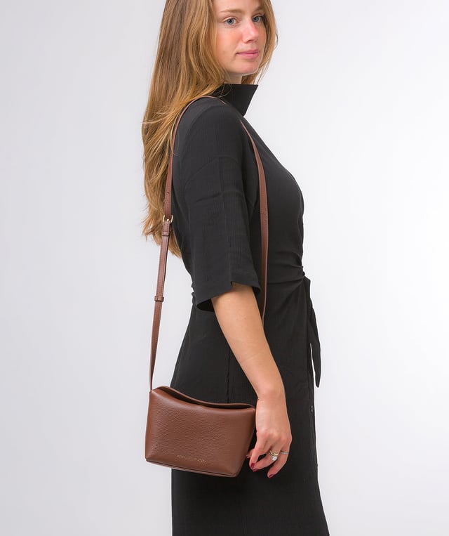 The 'Lolo' cross body bag from the Pure Luxuries Marylebone collection is handcrafted from high-quality, genuine Nappa leather with a natural super-soft touch. The bag is secured by a magnetic closure which opens to reveal a 100% cotton-lined interior and includes two slip pockets. Features gold-coloured metal fittings alongside the adjustable slim leather strap, with a maximum drop length of 65cm. The Pure Luxuries logo is embossed in gold foil for a beautifully simple finishing touch.