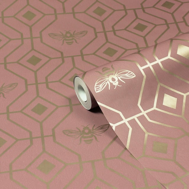 Make your boudoir buzz with the Bee Deco wallpaper featuring a honeycomb inspired geometric design completed with buzzing bumble bees. A soft blush hue sits behind metallic gold foil, bringing a contemporary colour scheme into your home. This wallpaper is a paste the wall application; simply paste the wall, hang your paper, and leave to dry. Each roll is 10m long and 52cm wide. Pattern repeat: 53cm Straight match. Our Bee Deco wallpaper can be used to paper the whole room or to create an eye-catching feature wall. This wallpaper is also wipeable so that any light marks can be dabbed away.