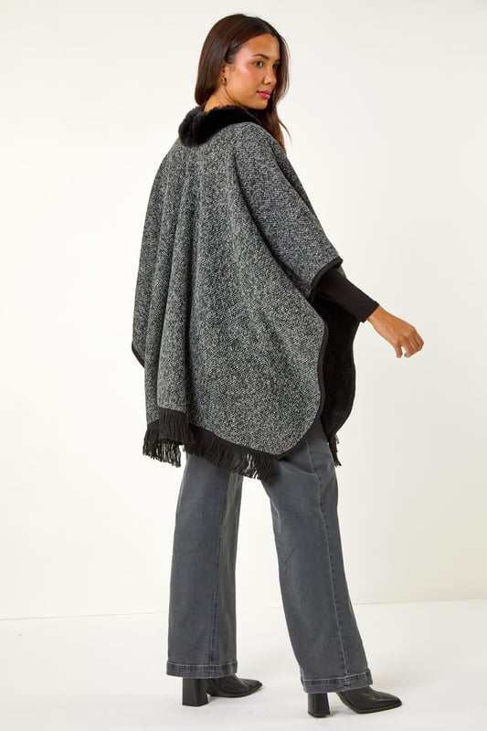 Faux Fur Fringe Hem Poncho from Roman. This style is ONE size.  Wrap up in style with this chic fringe detail poncho. Featuring a luxurious fur trim collar for added elegance and a trendy fringe hem for a playful finish, this poncho is the perfect layering piece for the Autumn/Winter season. Throw it on over your favourite knitwear and jeans for a fashion-forward look that will keep you both warm and stylish throughout the colder months!