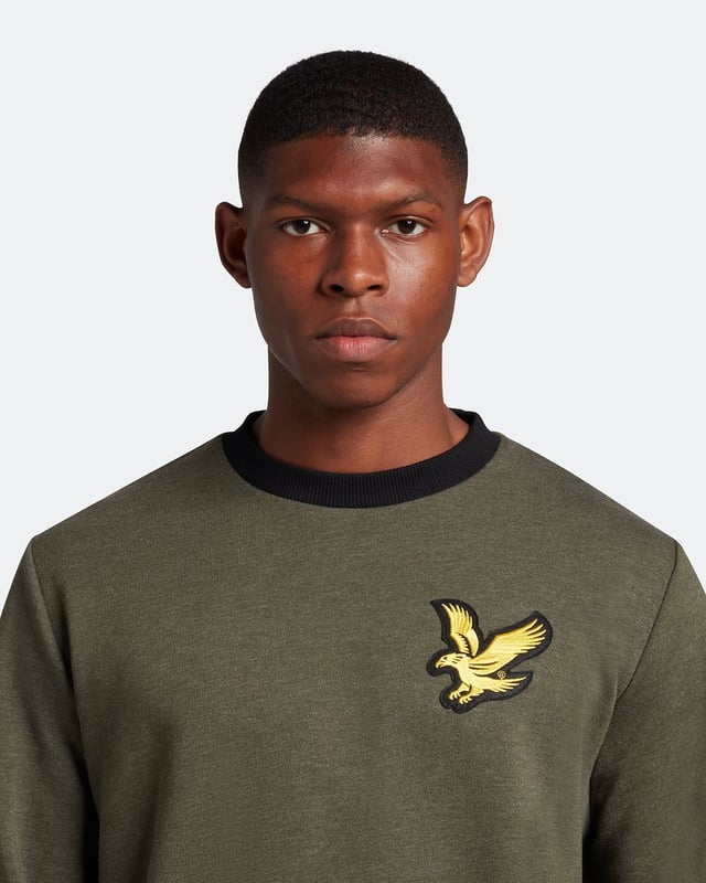 Suéter verde con logo de águila grande de Lyle & Scott. Manténgase cómodo y con estilo con el jersey Lyle & Scott Branded. Este jersey se ajusta a la talla real y presenta el logotipo de la marca Lyle & Scott. ¡Hacer una declaración nunca se vio ni se sintió tan bien! Dobladillo y puños elásticos, jersey de cuello redondo, suéter verde Lyle & Scott. 64% algodón, 36% poliéster, logotipo de la marca en el lado izquierdo del pecho. Ajuste regular, se ajusta a la talla real. Código de estilo: ML1727V W814