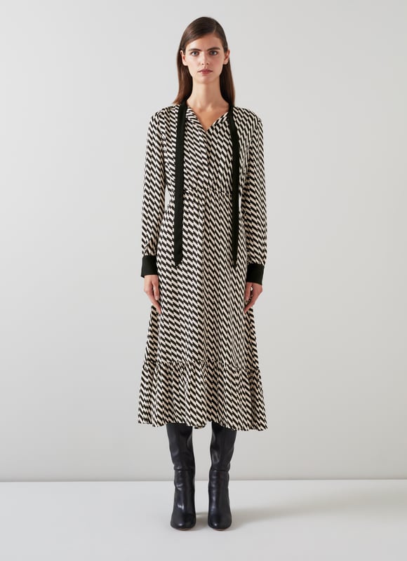 Effortless sophistication with the Bridget graphic print dress in timeless black. This smart casual piece, crafted from high-quality viscose, features a geometric design, adjustable neck tie, and convenient pull-on style. Perfectly pairs with sleek boots or classic heels for a refined look.