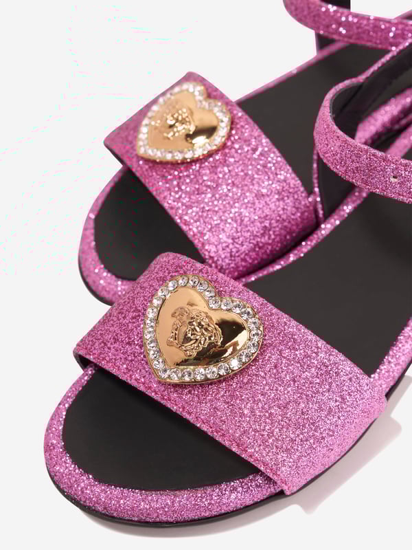 Presenting the luxurious Girls Medusa Heart Sandals in Pink by Versace. A summer essential, these sandals blend sophistication and comfort for your little girl's outings. Major highlights include: Made in Italy: Expertly crafted with the most exquisite detail, we promise durability and long-lasting use that Versace stands for. Medusa Heart Motif: These sandals feature a trendy Medusa heart motif, rendering a playful yet stylish appeal that promises to make your girl stand out. Premium Comfort: Made from top-notch materials ensuring maximum comfort for your little girl feet, allowing her to enjoy her summer adventures. Add a touch of elegance to your girl's wardrobe with Versace's Medusa Heart Sandals in Pink. Shop now, for an infusion of Italian sophistication into her style!