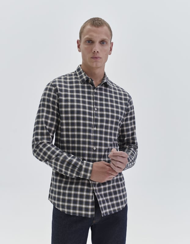 This navy shirt has collared neck and long sleeves. The shape is slim and short, with checked pattern.