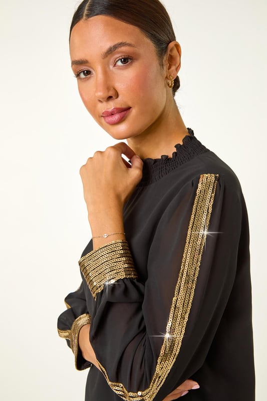 Sequin Stripe High Neck Sleeve Top from Roman. Make a sparkling statement in this elegant high neck sleeve top. Adorned with a glitzy gold sequin stripe running down the sleeve, finished with a dazzling sequin cuff. The long sleeves and high neck add sophistication to this top, making it perfect for the Autumn/Winter season. Pair with tailored trousers and heels for a stylish evening look that will surely turn heads!