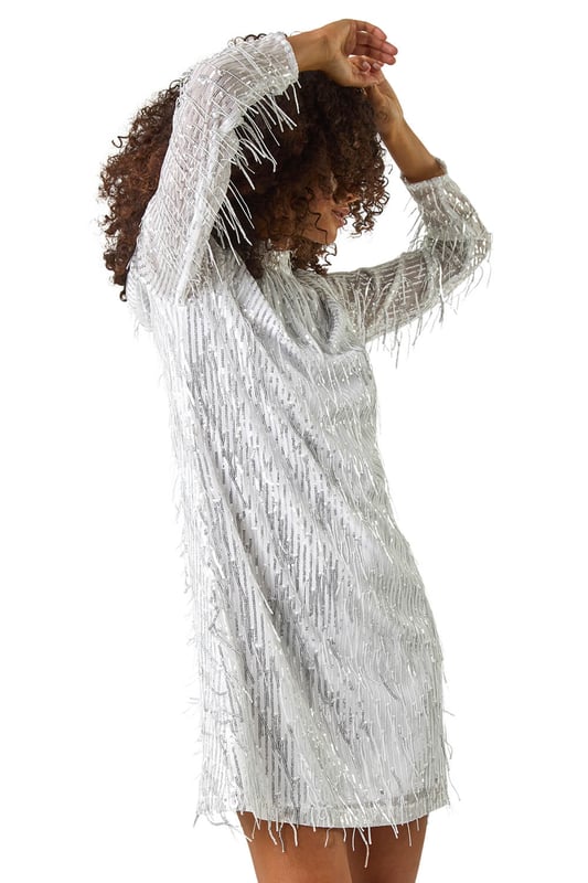 Dusk All Over Fringe Shift Dress from Roman. Get ready to make a statement in this eye catching all over fringe dress. The shift style creates a relaxed silhouette while the knee length finish adds a touch of sophistication. The black fringe detailing all over adds a fun and playful element to this chic dress. Pair with tights and heels to elevate your evening look with a touch of glamour!