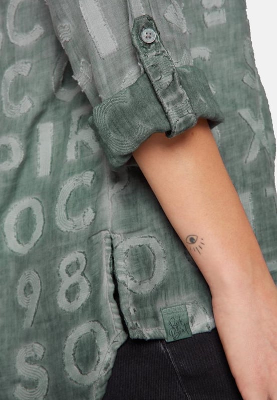 Deze blouse voor dames is een veelzijdige basic. Het heeft een losse pasvorm en is gemaakt van hoogwaardige materialen. De tuniekhals eindigt in een doorlopende knoopsluiting. De zoom is aan beide kanten gesplitst en heeft een langer, afgerond ruggedeelte. De lange mouwen zijn voorzien van interne knoopsluitingen zodat de mouw kan worden opgerold en vastgezet. De bijzondere kleurstelling van de binnenkant en het ingeweven logopatroon geven de blouse een heel bijzondere uitstraling.