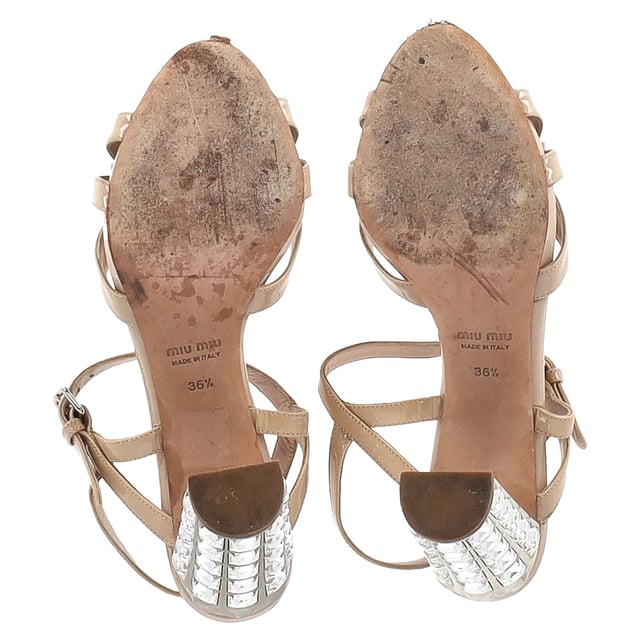 VINTAGE, UVP WIE NEU  
Die Miu Miu Sandalen mit Schleifen-Detail und Knöchelriemen in nude Lackleder sind der Inbegriff glamouröser Eleganz. Aus luxuriösem nude Lackleder gefertigt, verfügen diese Sandalen über ein zartes Schleifen-Detail an der Zehe, das dem Design eine verspielte und gleichzeitig raffinierte Note verleiht. Der Knöchelriemen sorgt für einen sicheren und schmeichelhaften Sitz, während der mit Kristallen besetzte Absatz ein funkelndes, hochmodisches Statement setzt, das jedes Outfit aufwertet. Perfekt für besondere Anlässe oder einen eleganten Abend, bringen diese Miu Miu Sandalen eine einzigartige Kombination aus Feminität, Luxus und glitzerndem Glamour in Ihre Schuhkollektion.   

Miu Miu Sandalen mit Schleifen-Detail und Knöchelriemen in nude Lackleder  

Zustand: Sehr gut  
Gebrauchsspuren: Geringe Abnutzung, leicht gebraucht, aber sehr gut gepflegt. Leichte Markierung an den Sohlen und Faltenbildung, leichte Kratzer an Sohlen und Absätzen.  
Verpackung: Keine  
Farbe: Braun | nude  
Material: Leder | Lackleder  
Größe: EU | 36.5/UK3.5/US6.5  
SKU: NAPPUGBSH444498W
