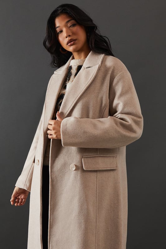 Double-breasted design for a sophisticated silhouette
        Maxi length offering full coverage and dramatic flair
        Wide lapels adding a touch of classic elegance
        Flap pockets for both style and functionality
        Relaxed fit allowing for layering versatility
    
    Make a statement with this striking double-breasted maxi coat from Warehouse. Perfect for the confident woman who appreciates edgy yet feminine style, this coat seamlessly transitions from day to night. The oversized silhouette exudes effortless chic, while the maxi length adds drama to any ensemble. Style it over wide-leg trousers and a chunky knit jumper for a contemporary daytime look. For evening affairs, drape it over a sleek midi dress and pair with heeled boots to create a captivating outfit. The versatile design allows for endless styling possibilities, making it a true wardrobe staple that will serve you well for seasons to come. Whether you're heading to the office or out for dinner, this coat will ensure you arrive in style.