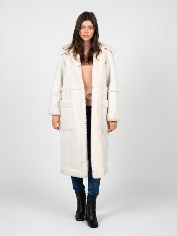 De jas van imitatiebont is de perfecte combinatie van elegantie en comfort, geschikt voor elke situatie, ongeacht de gelegenheid.

De uniforme kleur van de jas maakt hem extreem veelzijdig en makkelijk te combineren met verschillende stijlen, van casual tot meer formeel.

Grote metalen knopen met een merkelement geven de jas een uniek karakter en benadrukken de hoge kwaliteit en aandacht voor detail.

Diepe zakken aan de voorkant voegen niet alleen functionaliteit toe door het opbergen van noodzakelijke kleine items, maar zorgen ook voor extra comfort en warmte op koelere dagen.