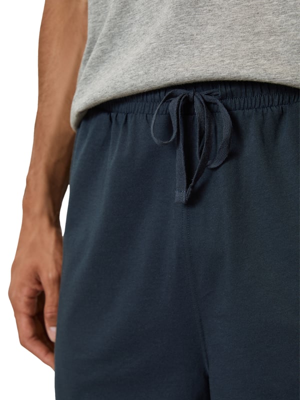 Deze tweedelige pyjama voor heren biedt perfect comfort voor ontspannen nachten. De top heeft een ronde halslijn en verlaagde schouders voor een losse en comfortabele pasvorm. De rechte zoom en logoprint op de voorkant geven de pyjama een moderne look. De shorts hebben een elastische tailleband en een trekkoord in de tailleband voor een optimale pasvorm. Deze pyjama is gemaakt van zacht, ademend materiaal en is zeer comfortabel om te dragen. Deze pyjama is ideaal voor warme zomeravonden of gezellige uurtjes thuis en is de perfecte keuze voor stijlbewuste mannen.