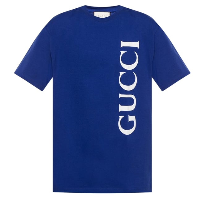Gucci blauw T-shirt, 100% katoen, gemaakt in Italie, groot merklogo verticaal aan de linkerkant van het T-shirt, dit T-shirt heeft een normale pasvorm. Het is raadzaam om je normale maat te kopen. Als je een kleinere bouw hebt, past de maat kleiner wellicht beter. 
