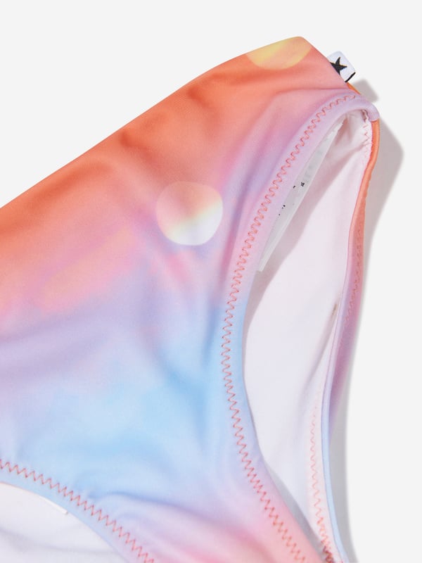 Introducing the Girls Sun Print Nikkie Asymmetrical Bikini In Orange by Molo, an essential add-on to your little girl's summer wardrobe! Here are its standout features:  Boutique Design: Flaunts an asymmetrical cut, lending a trendy, high-fashion look. Vivid Sun Print: The vibrant sun print in orange is playful and attractive, ensuring your little one shines brighter than the summer sun. Premium Quality: Crafted from superior fabric, this bikini promises utmost comfort and an excellent fit. Perfect for Summer: Its radiant colour and quirky design make it an ideal piece for beach days or pool parties.Add this Girls Sun Print Nikkie Asymmetrical Bikini In Orange from Molo to your cart and let your girl embrace summer in style!