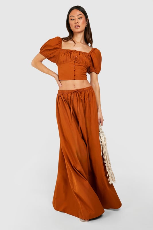 Plunging square neckline for a daring look
        Puff sleeves add a romantic touch
        Button-down front detail for adjustable styling
        Cropped length to showcase your midriff
        Fitted waist creates a flattering silhouette
    
    Make a statement in this eye-catching crop top that combines vintage charm with modern flair. The plunging neckline and puff sleeves create a captivating contrast, perfect for those looking to turn heads on a night out. Pair it with the matching high-waisted skirt for a coordinated ensemble that's sure to impress at your next social gathering. For a more casual look, team it with high-waisted jeans and trainers. The versatile design allows for easy transition from day to night - simply swap your footwear and add some bold jewellery to elevate your outfit for evening drinks or dancing. This Boohoo piece is ideal for the fashion-forward woman who isn't afraid to showcase her style and confidence.