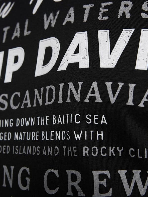Dieses Herren-T-Shirt kombiniert modernes Design mit sportlichen Akzenten. Die normale Passform und der Rundhalsausschnitt mit Rippblende sorgen für einen klassischen Look, während ein gestreiftes Necktape im Inneren einen Hauch von Raffinesse hinzufügt. Kontrastnähte an den Schultern setzen dynamische Akzente und betonen die maskuline Silhouette. Der Front-Print mit Rubber-Details verleiht dem Shirt einen coolen, strukturierten Look. Ein kleiner Logo-Print auf der Rückseite und ein Label-Patch am linken Ärmel runden das Design ab. Das weiche Material bietet höchsten Tragekomfort, ideal für jeden Tag. Ein perfektes Shirt für den stilbewussten Mann, der Wert auf Details legt. Ob lässig oder sportlich, dieses T-Shirt ist ein echter Hingucker.