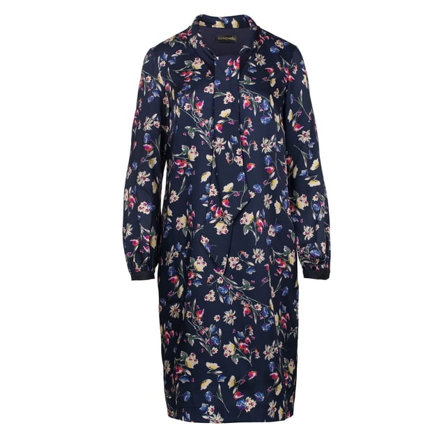 Este vestido estampado floral está confeccionado en viscosa satinada. El cuello se abrocha en la parte delantera con dos lazos en la misma tela. Tiene mangas largas y hay tela de contraste en los puños que se abrocha con un botón. El vestido tiene una longitud hasta la rodilla y tiene una silueta suelta. Está completamente forrado.