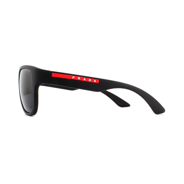 Prada Sport Sunglasses PS01US DG05S0 Black Rubber Grey are an easy to wear rectangular style. The bold style features thick temples with the red Prada Sport logo. A rubberised finish gives a sporty feel and the rubber inserts on the insides of the temples help to hold the sunglasses in place..
