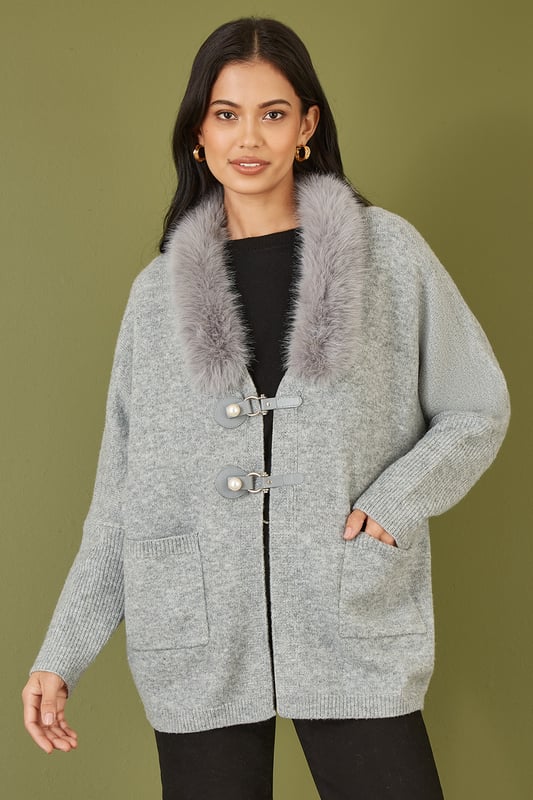 This cute cardi is perfect for cosying up this winter - In a soft marl knit with buckle fastening in the front and faux fur detachable collar. Style with jeans and a roll neck jumper - With boots or trainers for a casual off duty look.