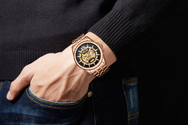 "Die Anthony James Hand Assembled Limited Edition Mystique Automatic Rose Herrenuhr verfügt über ein 21-Rubin-Uhrwerk mit 162 Teilen und eine hervorragende Präzision, die durch das skelettierte Goldzifferblatt hervorgehoben wird, das einen kühnen Kontrast zum schwarzen Rand bildet, und dieselbe Technik ist vom Gehäuseboden aus sichtbar. Die Uhr ist wasserdicht bis 3ATM und das kratzfeste Mineralglas ist anspruchsvoll und zuverlässig zugleich. Das rosafarbene Edelstahlarmband fixiert die Uhr, die mit einer fünfjährigen Garantie ausgestattet ist. " "Eigenschaften der Uhr - Automatikwerk - Handgefertigtes 162-teiliges Uhrwerk mit 21 Rubinen - Skelettiertes schwarzes und goldenes Zifferblatt - Wasserdicht 3ATM - Kratzfestes Mineralglas - 5 Jahre Garantie Maße und Gewichte - Gehäusedurchmesser 42 mm -. Dicke des Gehäuses 14 mm - Breite der Hörner 22 mm - Breite des Armbands 20 mm - Länge des Armbands 220 mm - Gewicht 123 Gramm Materialien und Farben - Stahl und Bo&amp;tier-Legierung - Skelettboden - Rosafarbenes Edelstahlarmband - Sicherheitsfaltschließe mit Logo - Krone mit Logo".