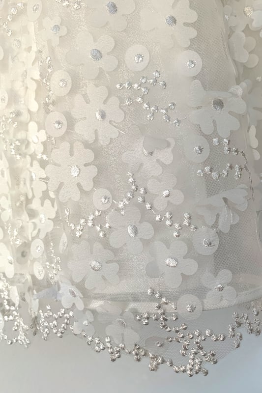 We always say 'it's in the detail' but it truly is with this style. The detail is in the amazing fabric! 3D Organza flowers attached with embroidered centres to Tulle.
We made the top of the dress in contrasting plain organza and finished it with pearl beads around the neck to give the impression of a necklace.
Suitable for baby and toddler girls, it is lined in 100% lighweight cotton lawn making it soft and comfy against your child's skin. Also good for girls with sensitive skin.
Style: KALI is ideal for Christenings, Baptisms, naming ceremonies, Flower girl or any other special occassion or family event!
Why not complete the look with one of our caridgans. Take a look at style VALENTINA. It too has pearls around the neck so would compliment this dress really well.
Finish off with a headband. LANA or MABEL would look equally beautiful.
All our dresses arrive with you on a Satin padded hanger, to help keep it's shape and protected by a Heritage garment keepsake bag.
Outer - 100% Polyester
lining - 100% cotton
Dry clean or Hand Wash