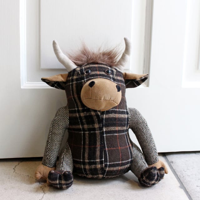 Alastair the Highland Cow is a novelty doorstop. Alastair is a plethora of patterns including a tartan body, feet and inner ears, plain outer ears, snout and hands. Complete with a cute tuft of hair on his head ad on the tip of his tail. Made of 100% polyester with a base filled with sand making Alastair heavy enough to hold open most doors. Alastair is spot clean only.